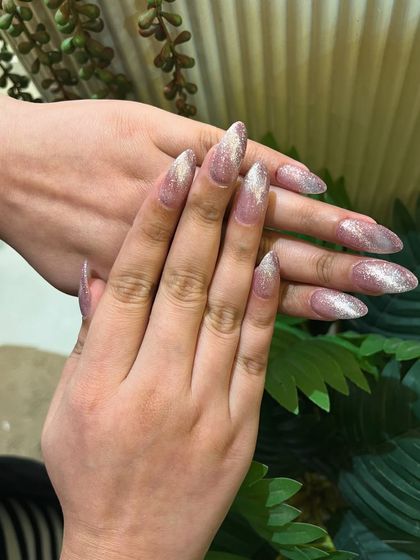 A full set of long, stiletto-shaped extensions with a silver cat eye polish. The effect creates a beautiful diagonal shimmer across each nail.