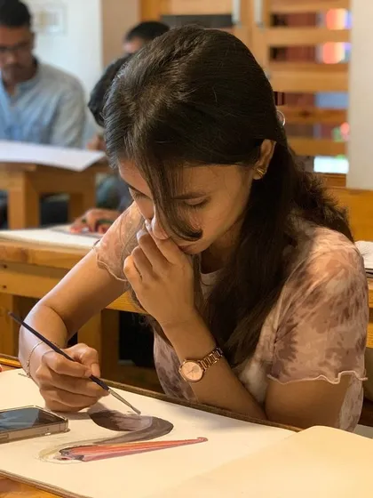 A student carefully works on a portrait, her focus unbroken. The serene environment we cultivate is essential for the detailed work required in portraiture.