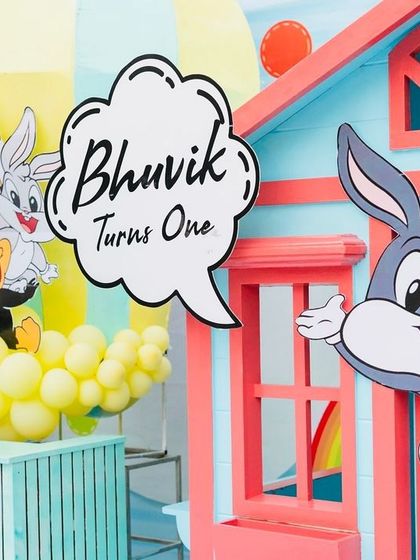 A welcome sign for "Bhuvik Turns One," featuring Bugs Bunny and other Looney Tunes characters.
