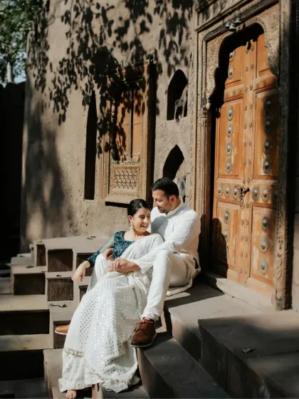An intimate, sun-dappled moment on the steps of a heritage building. The play of light and shadow from the leaves above adds a natural, romantic feel to this candid couple portrait.