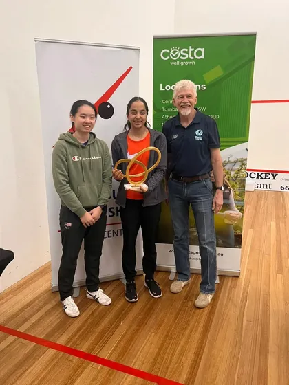 Tanvi Khanna with her first PSA title at the Costa North Coast Squash Open in Australia. She stands alongside her final opponent and a tournament official, marking a significant career milestone.