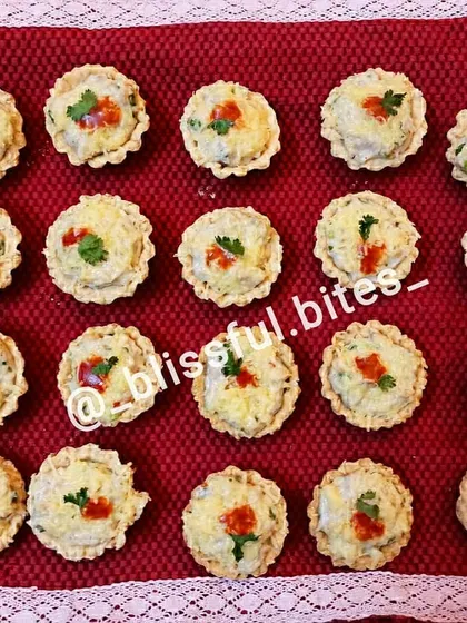My savoury chicken tarts arranged on a red cloth, ready to be served. The creamy filling and crisp pastry make them an irresistible appetizer.