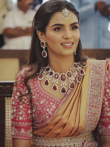 A South Indian bride in a beautiful silk saree, adorned with a stunning ruby and diamond necklace. This demonstrates my expertise in styling for different cultural weddings.