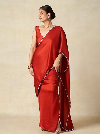 A full-length look for Gulabo by Abu Sandeep. The makeup is sophisticated with a clean bun hairstyle, creating a timeless look for this vibrant red saree.