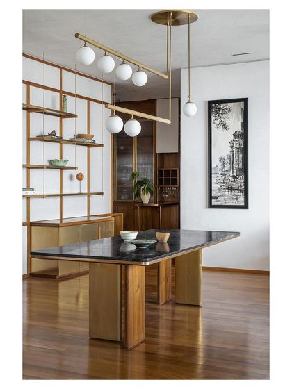 Another perspective of the dining room, emphasizing the custom table and the light, open-shelf divider that separates the space without closing it off.