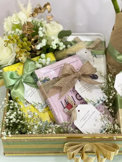 A close-up view of the gift items within the wellness hamper. The books and other goodies are tied with rustic jute ribbons, reinforcing the natural and sustainable theme of the gift.