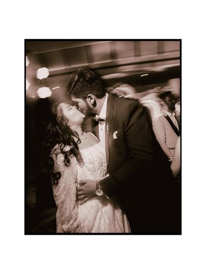 A stolen kiss amidst the motion of the dance floor. The blur and warm tones give this image a dreamy, romantic feel, capturing a private moment in a public celebration.