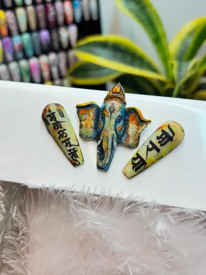 Another angle of our detailed Ganpati nail art, showing the fine lines and color blending that bring the design to life.