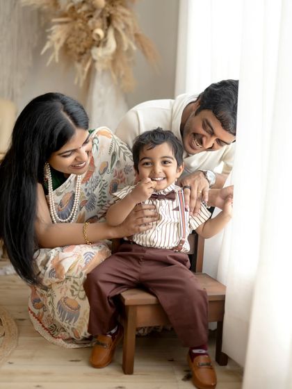 A family plays peek-a-boo by the window. The little boy's excited expression is the focal point of this fun and interactive family photo.