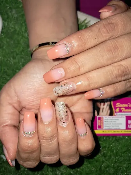 A soft and pretty peach ombre. This design features a gentle fade from nude to a warm peach color, with glitter and rhinestone accents for a touch of sparkle.