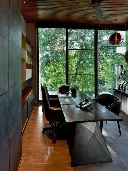 Another view of the T House study, highlighting the custom desk and the seamless connection to the outdoors. The design creates a workspace that feels like a tranquil treehouse, suspended in the green canopy.