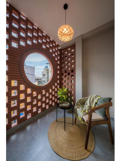 A view of the cozy balcony at the Mathrukrupa residence, featuring a comfortable armchair and a natural fiber rug, perfect for a quiet afternoon.