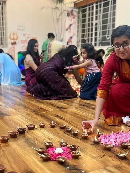 Two students collaborating on the diya arrangement. The path of yoga can be solitary, but the journey is made richer when shared with a supportive community.