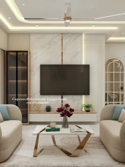 A modern living room with a floating TV unit set against a white marble panel. The curved sofas and metallic-finish coffee table add a soft, luxurious touch to the minimalist aesthetic.