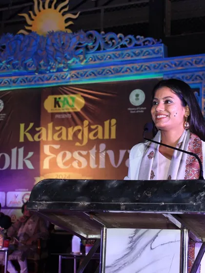 Smiling while speaking at the Kalanajali Folk Festival, feeling connected to the audience.