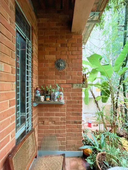 A quiet corner of the Sans Souci veranda, where the exposed compressed earth block walls create a warm, textured backdrop. Every part of the home is designed to connect with the surrounding nature.