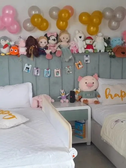 Simple birthday decorations in a child's bedroom, with balloons and stuffed animals arranged on the headboard.