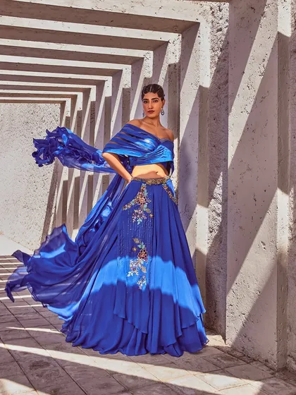 A vision in royal blue, this Miku Kumar ensemble features a stunning tie-dye effect skirt and an off-shoulder draped blouse. The flowing silhouette and vibrant colour make it a perfect choice for a sangeet or reception.