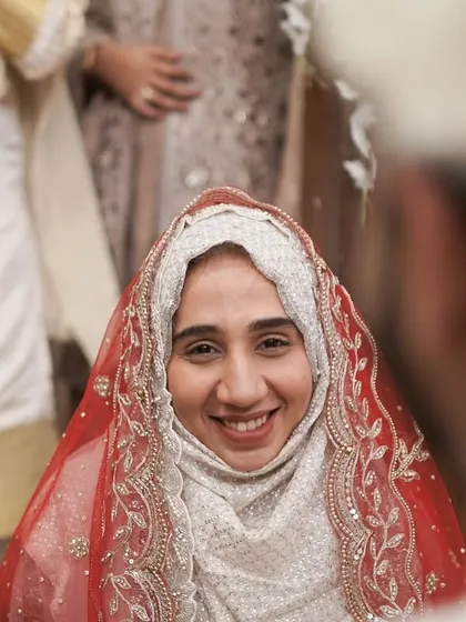 The bride's radiant smile as she looks at her groom during the Nikkah ceremony. This over-the-shoulder shot creates an intimate perspective, focusing entirely on her joyful expression.