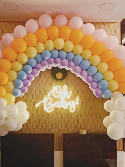 A full view of the rainbow balloon arch, perfect as a photo backdrop or to frame the main seating area for the parents-to-be.