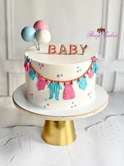A sweet celebration for a little one on the way. This baby shower cake is decorated with a clothesline of tiny pink and blue fondant baby clothes, perfect for any parent-to-be.