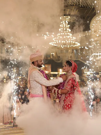 A magical moment as the couple exchanges garlands amidst a cloud of smoke and sparklers.