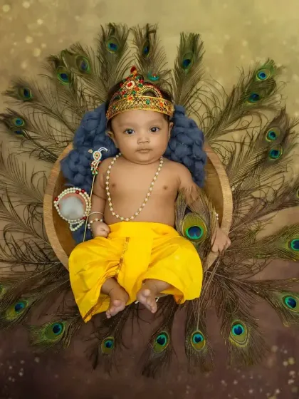 An overhead shot of the full Krishna setup, with the baby lying in a basket surrounded by a fan of peacock feathers.