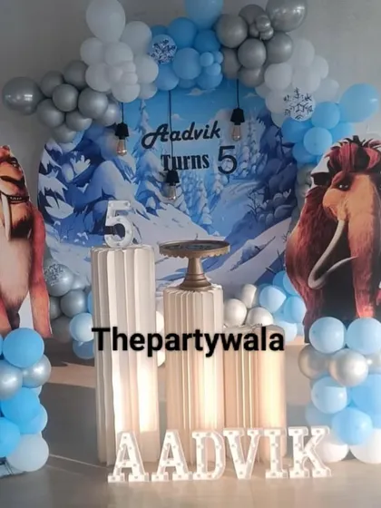 Let's go back in time with an Ice Age theme! This cool setup features a wintery backdrop and cutouts of Manny and Diego, with a blue and silver balloon arch.