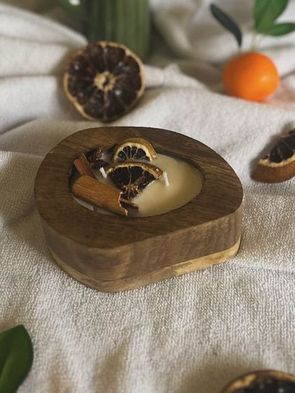 Capturing the cozy feeling of autumn with this special scented candle. It's poured in a rustic wooden bowl and topped with dried orange slices and cinnamon sticks for a warm, spicy citrus aroma.