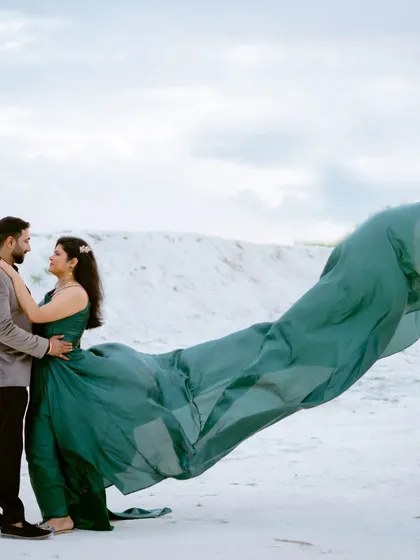 The wind catches the bride's green gown, creating a stunning, wing-like shape. This is a perfect example of how I work with natural elements to create dynamic and artistic pre-wedding photos.