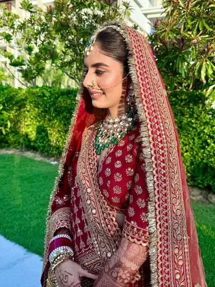 A bridal look that whispers timeless beauty. Wrapped in the golden hour embrace, Anmol radiates in red with soft matte eyes, glowing with love and a touch of tradition.