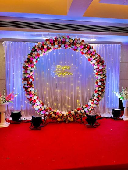 Another view of the popular floral ring backdrop for an engagement. The mix of red, pink, and white flowers creates a romantic and celebratory feel.