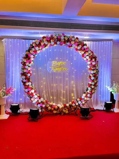 Another view of the popular floral ring backdrop for an engagement. The mix of red, pink, and white flowers creates a romantic and celebratory feel.