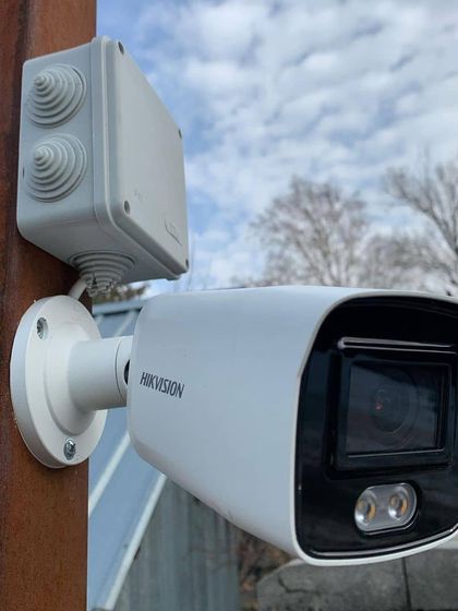 A close-up of a pole-mounted Hikvision camera with its junction box. This professional setup is ideal for monitoring parking lots, open fields, and large commercial perimeters.