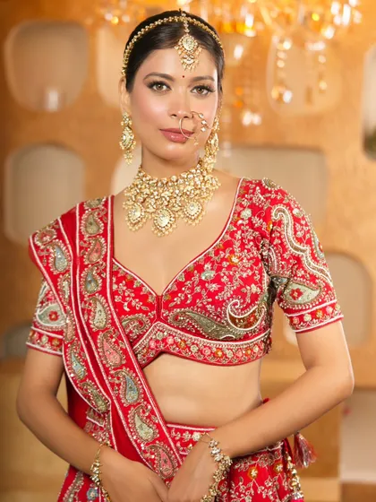 A full-length view of a bride in a red lehenga, showcasing how a complete Kundan set, including the choker and maang tikka, creates a stunning and traditional silhouette.