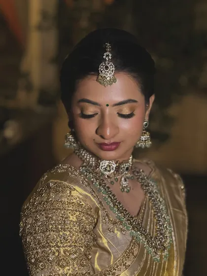 A close-up focusing on the intricate details of her diamond and emerald jewellery, which the makeup beautifully complements.