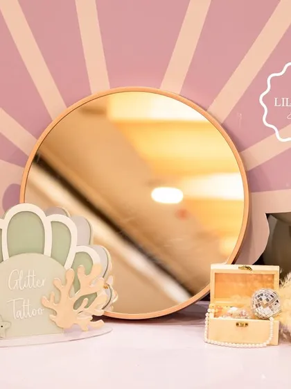 A glitter tattoo station at the mermaid party, set against a large seashell backdrop for a touch of underwater glamour.