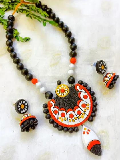 A beautiful necklace set with a fan-shaped pendant, here in a classic black, white, and orange color scheme.