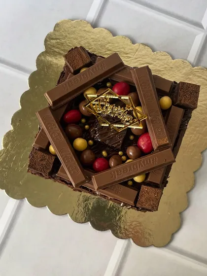 Indulge in pure decadence with our signature overloaded brownie cake. This eggless creation is layered with rich, fudgy brownies and topped with KitKat bars, chocolate spheres, and more for the ultimate celebration centerpiece.