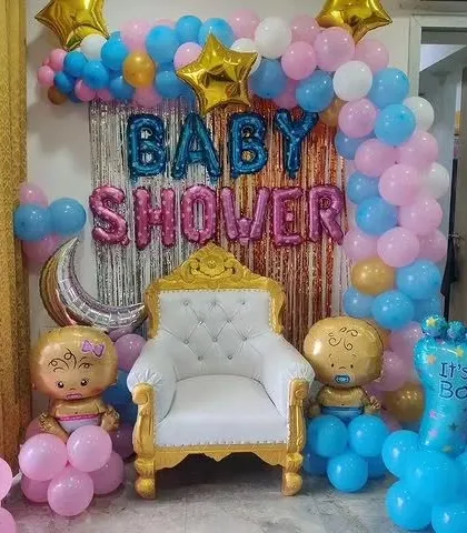A classic "He or She" baby shower theme with pink and blue balloons, a shimmer curtain, and a throne for the mom-to-be.