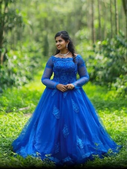 A true princess gown. This royal blue ball gown features intricate lace and beadwork on the bodice and a full, flowing skirt, perfect for a magical photoshoot in the woods.