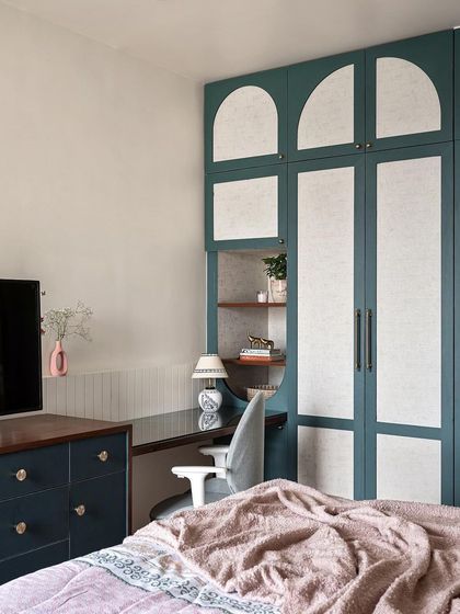 This additional wardrobe in the master bedroom has a more traditional charm, with fabric laminate panels and an arch-shaped design. A semi-circular niche provides an integrated study or vanity space.