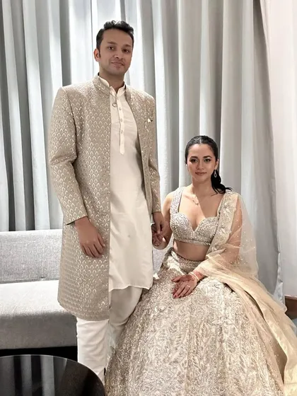 An elegant and timeless pairing in champagne gold. Her intricately embroidered lehenga is perfectly matched with his classic sherwani for a reception or wedding.