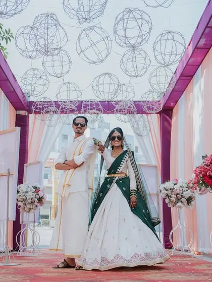 A stylish portrait of the couple at their Haldi event, posing with sunglasses in a beautifully decorated entryway.