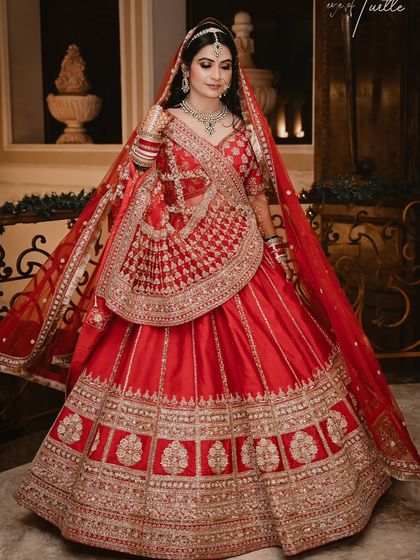 The complete bridal look in all its glory. This full-length portrait showcases the stunning detail of the red lehenga, capturing the bride's elegance and poise on her special day.