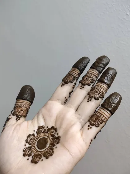 A simple and cute floral mandala on the palm with detailed finger bands.
