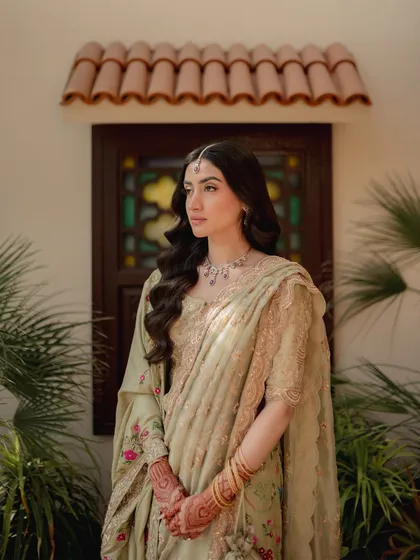 A portrait of quiet elegance. The bride-to-be, dressed in a beautiful pastel saree, is captured in a moment of serene contemplation, surrounded by natural beauty.