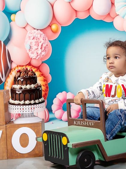 Vrooming into year two! This little boy celebrates his second birthday with a cool jeep prop and a donut-themed backdrop, ready for his next big adventure.