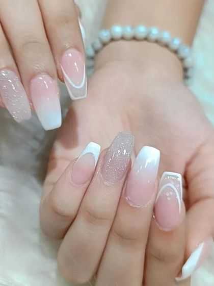 Another view of the mixed-style white and nude set, showing the different designs on each nail, including V-French and glitter.