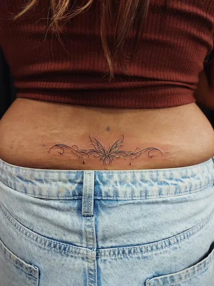 A delicate ornamental design for the lower back. This symmetrical, fine-line tattoo is an elegant and sensual piece of body art.